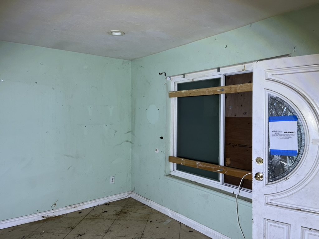 Briar Avenue living room before rehabilitation with boarded window